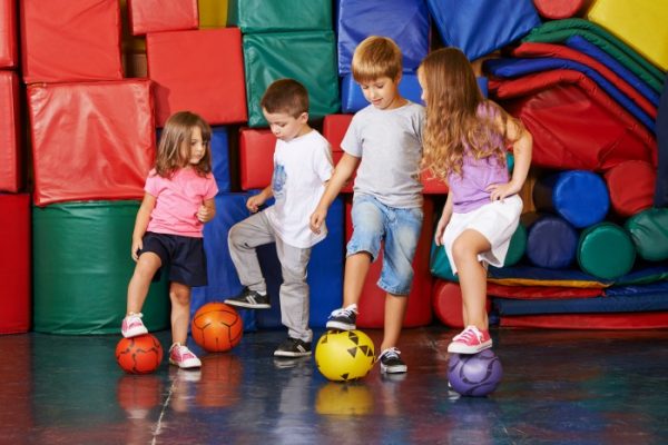 Kinder spielen mit Bällen Fußball in der Turnhalle vom Kindergarten
